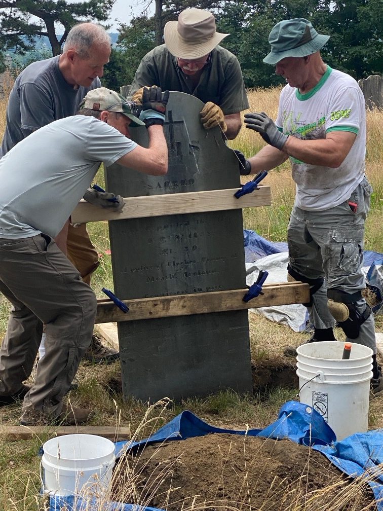 Sam Wilson (at right), Stewards&rsquo; treasurer, leads a crew resetting a slate grave marker